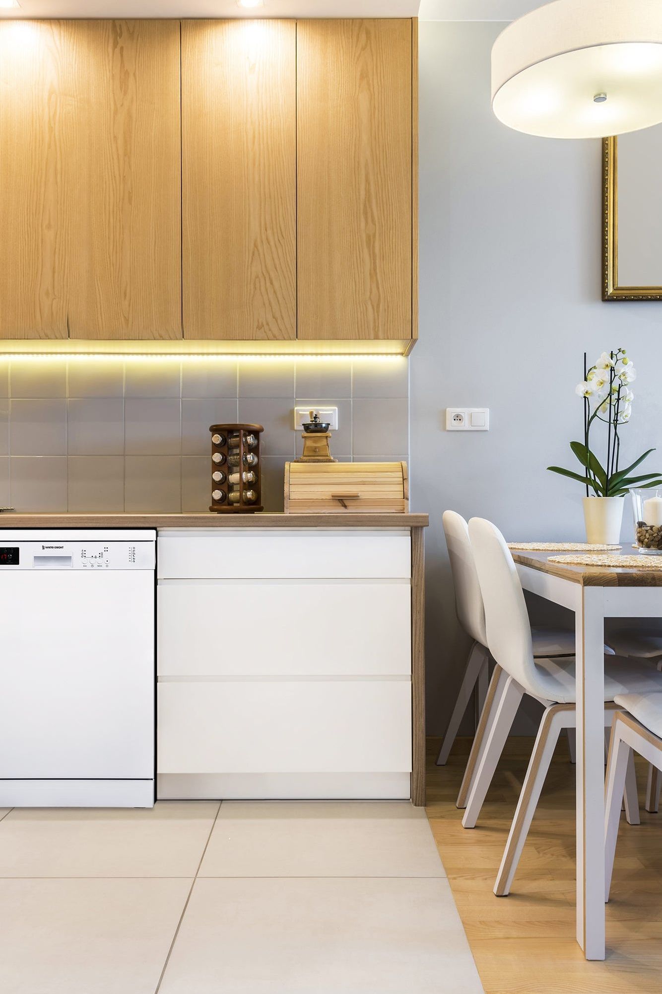 Modern kitchen with wooden cabinets, white appliances, and a dining area.