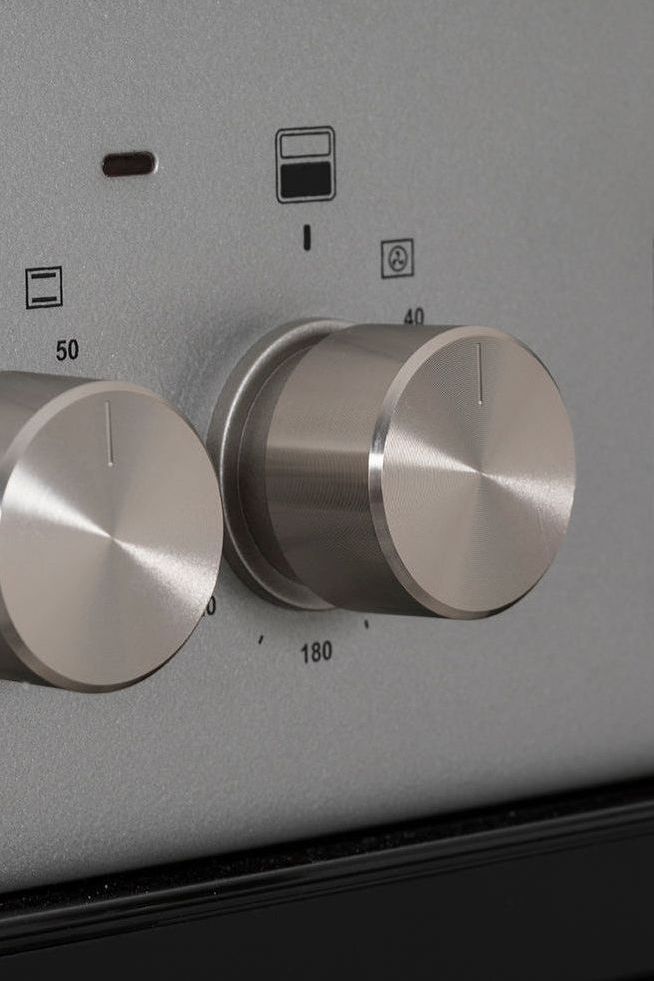 Stainless steel oven control panel with two knobs and digital display.